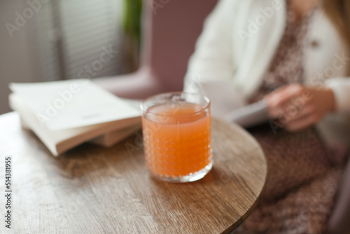 Cocktail or peach juice on the wooden table at cafe near the books. Student lifestyle, reading and studying. Woman spending time at cafe, having lunch or breakfast.