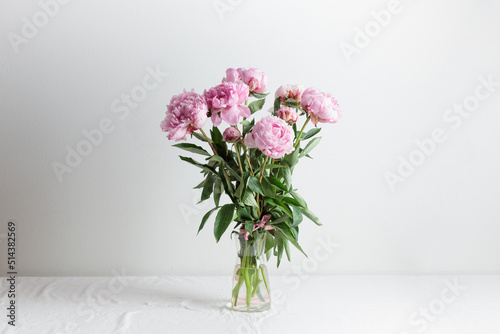 Beautiful bunch of fresh Pastel colored Pink peonies in full bloom in vase with white background