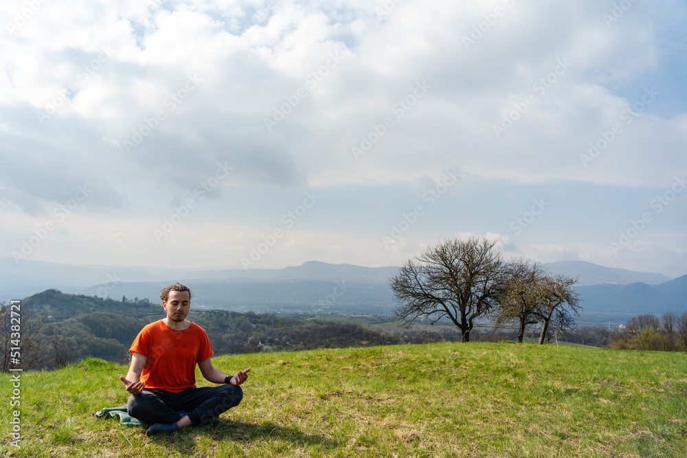 Young man do yoga on the mountain peak