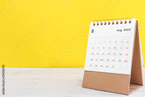 August calendar 2023 on wooden table on yellow background