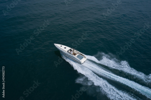 Big high speed white boat with a man at high speed top view. Open white boat fast motion on a dark aerial view. © Berg