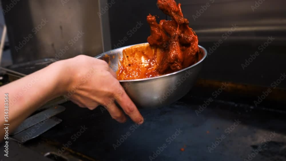 Chef tosses fried chicken wings in vibrant orange buffalo sauce, slow motion 4K