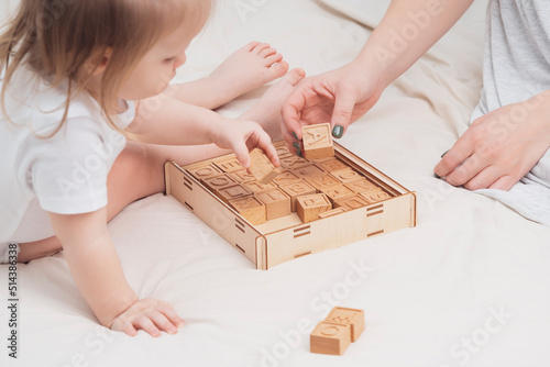 Mom and child are learning the English alphabet, close-up. The child plays with wooden cubes, with English letters. The concept of early development, preschool education at home. Educational games