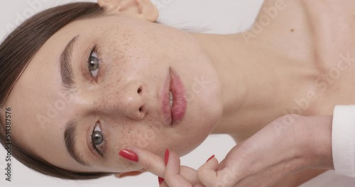 Woman applying face cream and smiling sincerely in studio