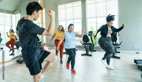 group of overweight girls in sportswear aerobic dance with their trainers workout in sport club .Relationship and fat girl exercising concept