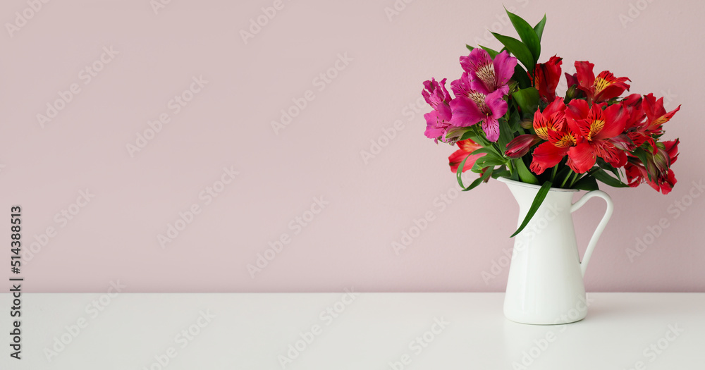 Vase with bouquet of beautiful alstroemeria flowers on table near light wall. Banner for design