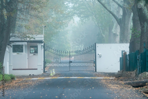 high security entrance to an estate driveway with closed metal gates and police guardhouse concept safety and security photo