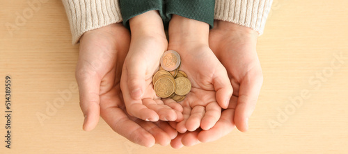 Photos Hands of man and his son holding coins on wooden background