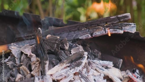 Coals from wood burn in a barbecue in nature.