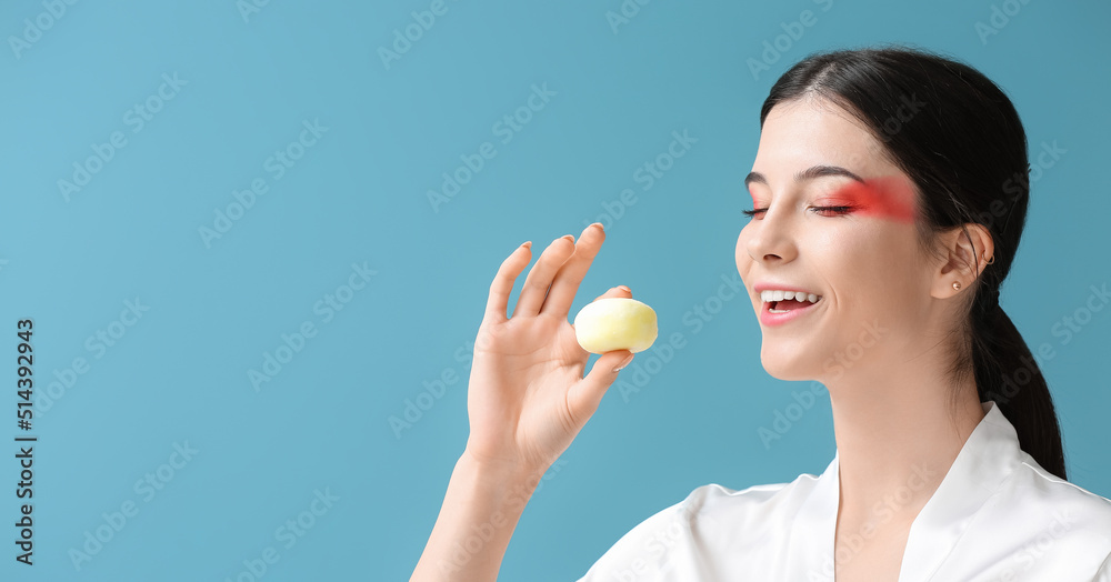Beautiful young woman with tasty Japanese mochi on blue background