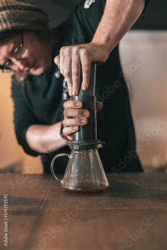 Professional Barista press to device and coffee drops pours trought aeropress to pot