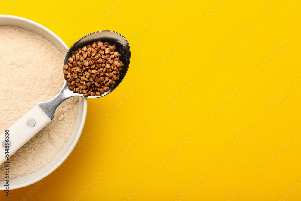Bowl of flour and spoon with buckwheat grains on yellow background Bowl of flour and spoon with buckwheat grains on yellow background