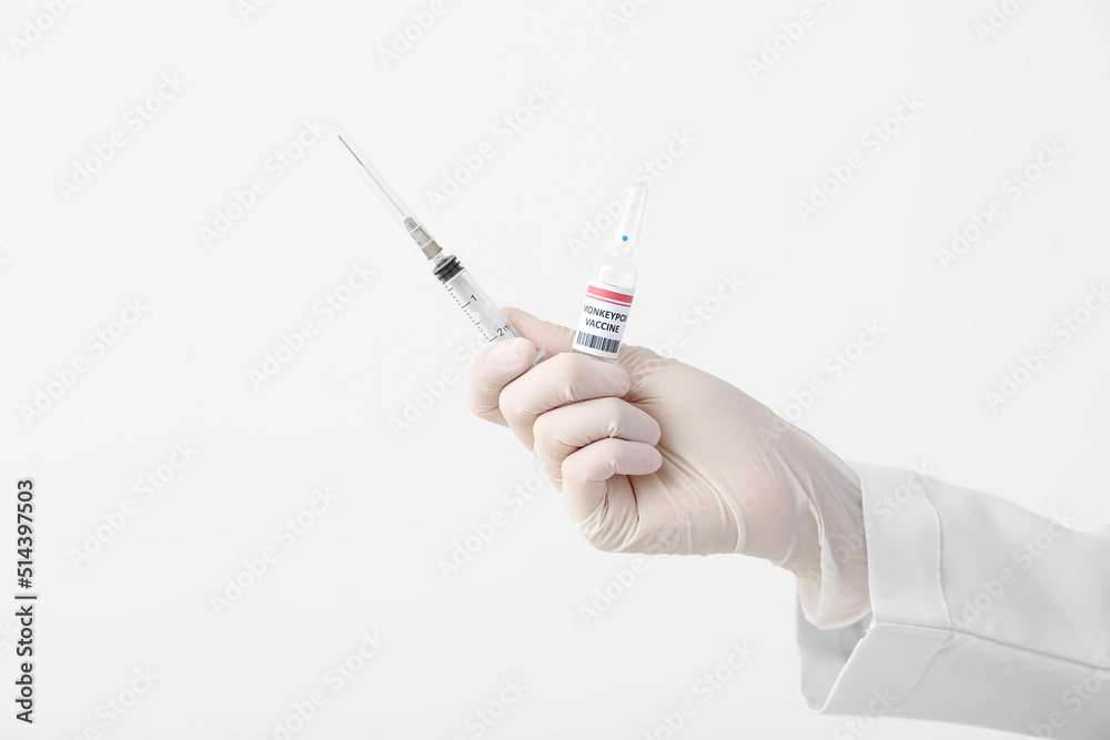 Female doctor with monkeypox vaccine and syringe on light background, closeup Female doctor with monkeypox vaccine and syringe on light background, closeup