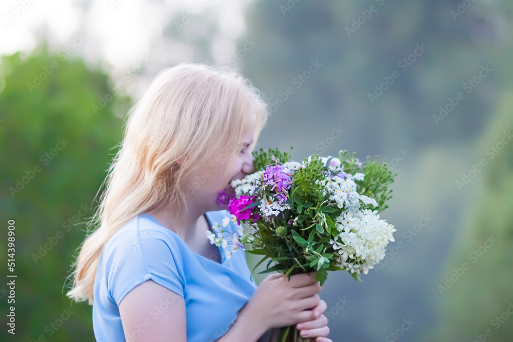 Beautiful young girl in blue dress holding the bouquet of wildflowers in her hands. Beautiful young girl in blue dress holding the bouquet of wildflowers in her hands.