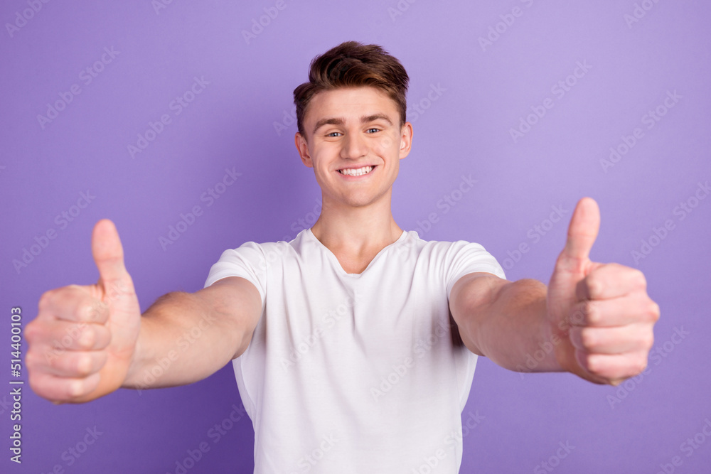 Portrait of cheerful man in basic clothing smiling showing thumbs up at camera isolated over shine background Portrait of cheerful man in basic clothing smiling showing thumbs up at camera isolated over shine background
