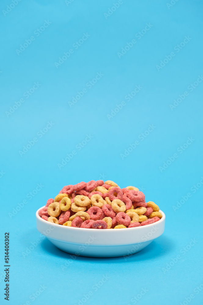 Quick cereal breakfast in the form of rings on a plate on a blue background Quick cereal breakfast in the form of rings on a plate on a blue background