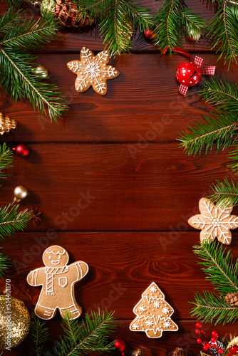 Vertical Christmas frame with real wooden green pine tree  colorful baubles  knots with berries and gingerbread on wooden background. View from above.