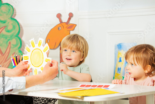 Teacher in kindergarten show sun card to the children