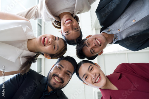 Foto Portrait closeup bottom view happy faces of employees team standing in circle, looking at camera