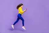 Full length body size view of beautiful trendy cheery girl jumping using device isolated over bright violet purple color background