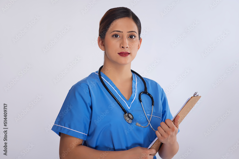 Portrait of a female nurse standing with clipboard in hand against white background Portrait of a female nurse standing with clipboard in hand against white background