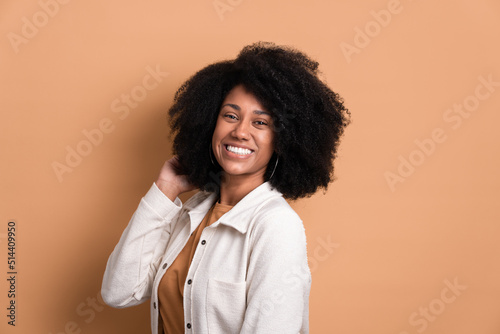 beautiful dark skinned woman touching hair wearing white jacket in studio shot. portrait, real people concept.