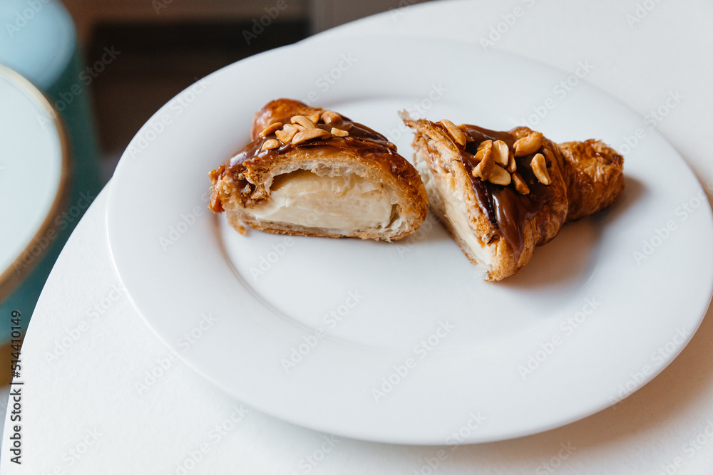 appetizing croissant with chocolate and peanuts on a plate appetizing croissant with chocolate and peanuts on a plate