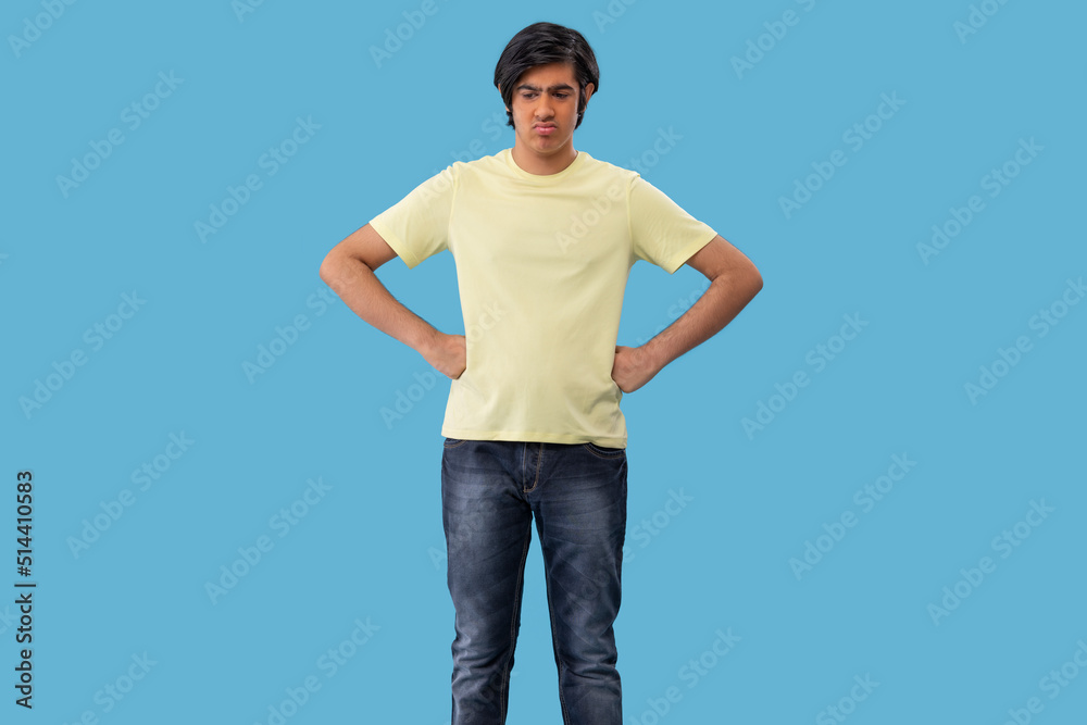 Portrait of a sad teenage boy standing against blue background Portrait of a sad teenage boy standing against blue background