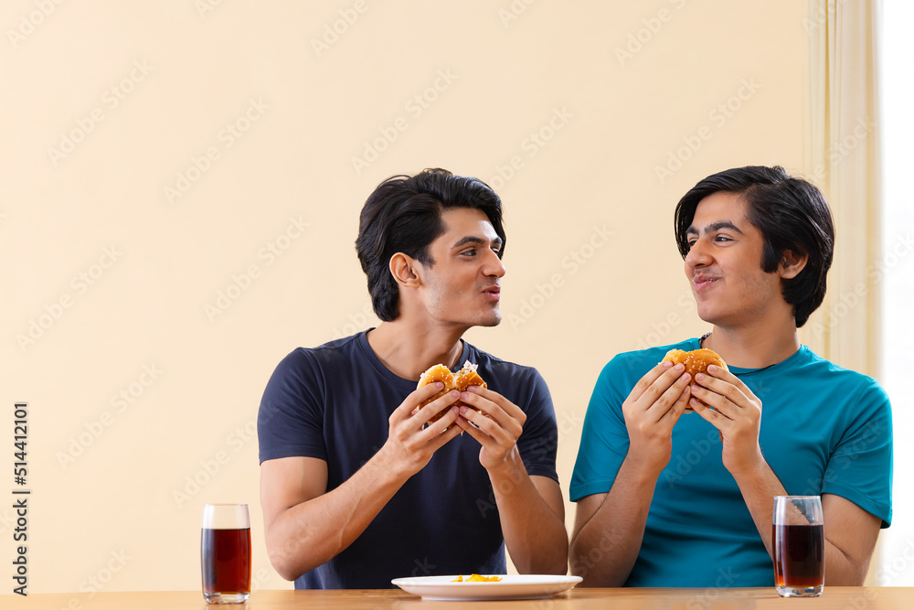 Portrait of teenage boys eating burgers together 
