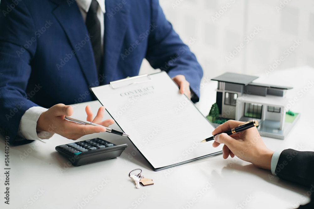 hand of young man customer signing contract for buying house with real estate broker in suit at estate agent office, investment, home loan contract, buying house, real estate and insurance concept hand of young man customer signing contract for buying house with real estate broker in suit at estate agent office, investment, home loan contract, buying house, real estate and insurance concept