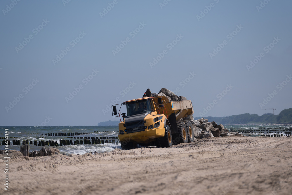 CONSTRUCTION DUMP TRUCK - A big vehicle carries boulders on the sea beach
