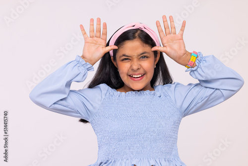 Fotografía Portrait of little girl making funny face against plain background