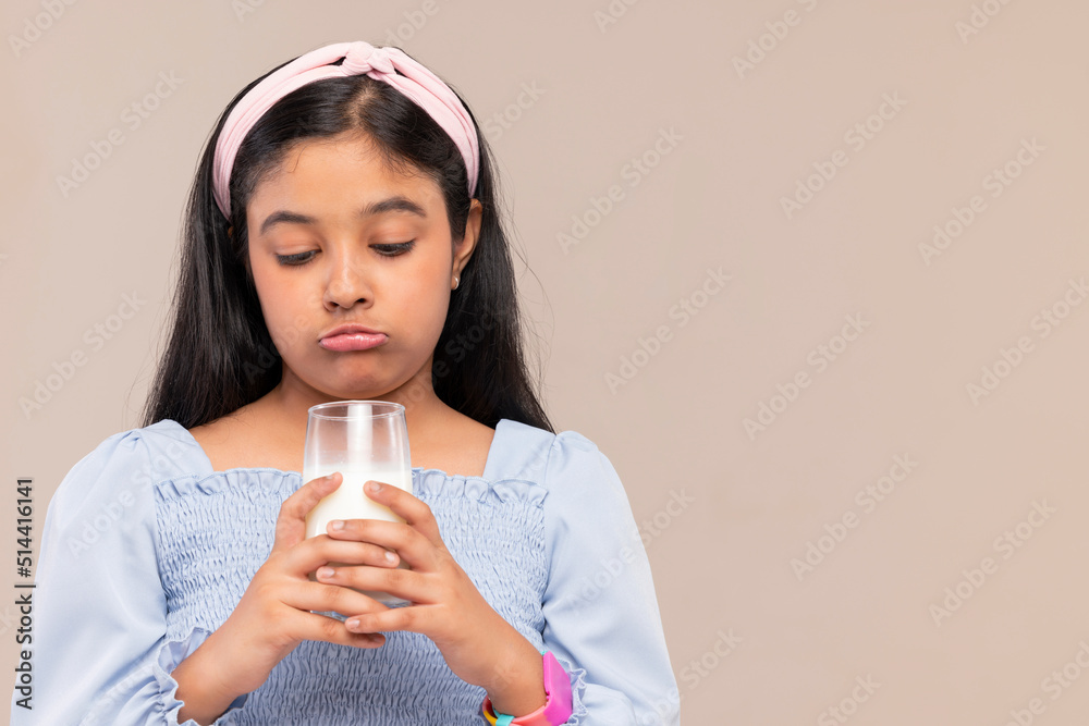 Portrait of little girl expressing unhappiness over a glass of milk in hand Portrait of little girl expressing unhappiness over a glass of milk in hand