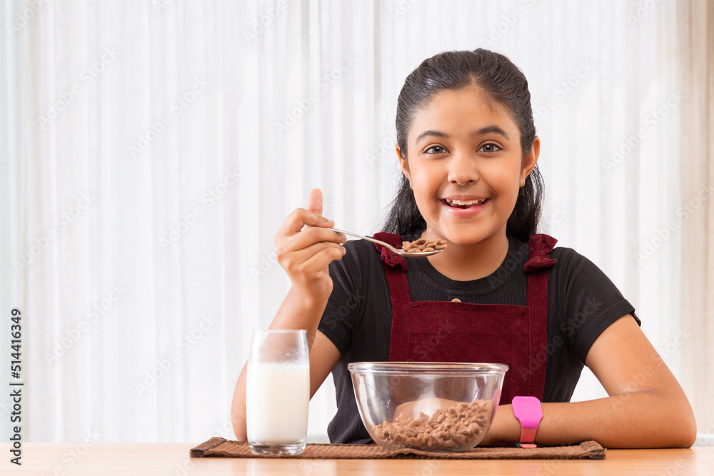 Portrait of cheerful little girl eating cereals at home Portrait of cheerful little girl eating cereals at home