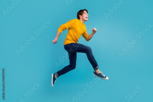 Profile side photo of guy full body run high hurry advertising on blue wall background studio shot