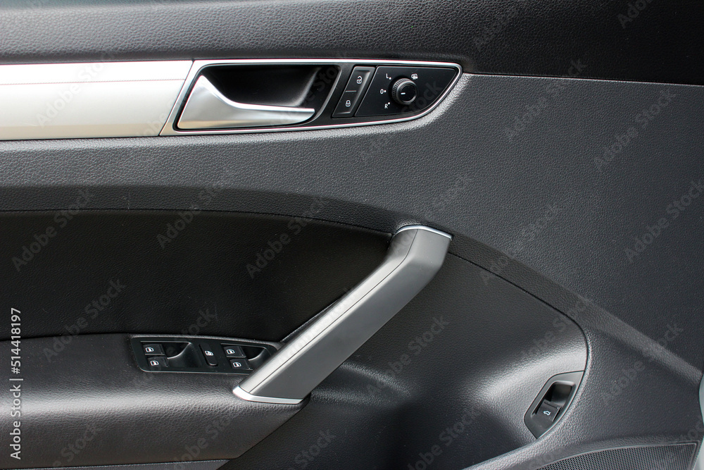 Door handle with windows controls and adjustments in black leather interior. Window switches.