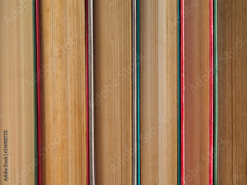 Abstract background of books standing vertically, a view of the book spines. Colorful hardcover books close-up.  A stack of hardcover books as a background, side view. Concept: education, training