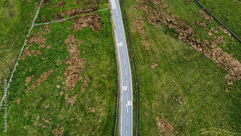 Aerial view looking down onto a road surrounded by farmland and countryside. Drone image taken in Lancashire England. 