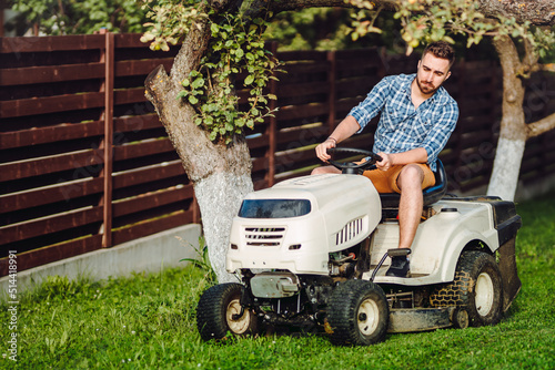 Professional gardener and lawn mower cuts the grass using tractor.