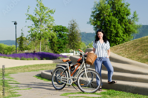 Happy brunette asian woman sitting, walking in city street. Sport bike. Park. laughing on a summer sunny day. Having fun. Lifestyle