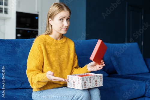 Dissatisfied woman with opened gift box looking at camera