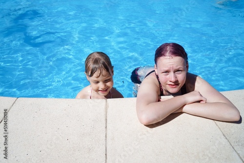 Two little sister girls in pool near side.