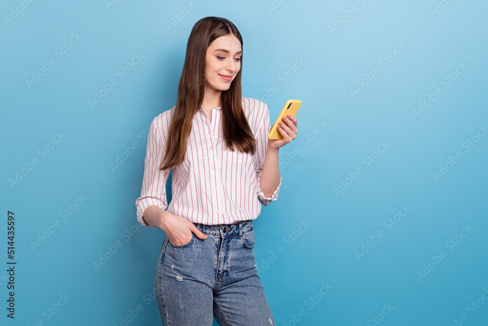 Portrait of attractive trendy cheerful focused girl using device application isolated over vivid blue color background Portrait of attractive trendy cheerful focused girl using device application isolated over vivid blue color background
