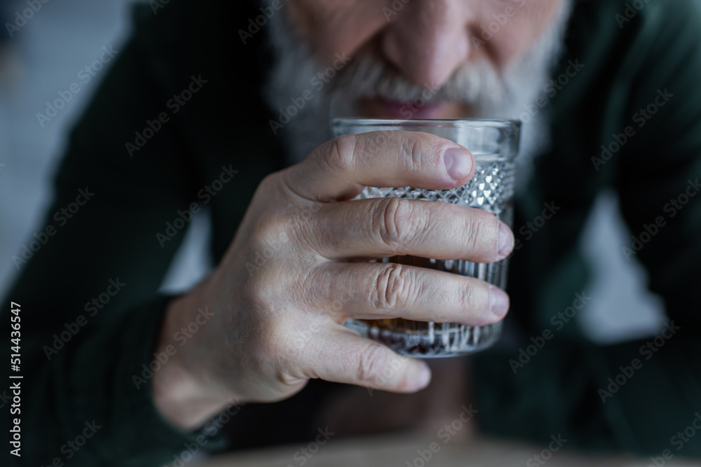 cropped view of senior man drinking whiskey while holding glass. cropped view of senior man drinking whiskey while holding glass.