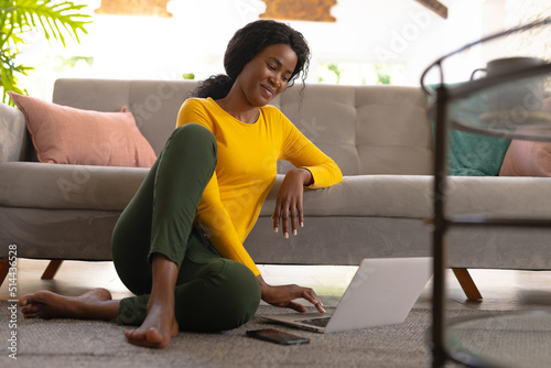 Young african american female freelancer using laptop while working from home, copy space photo