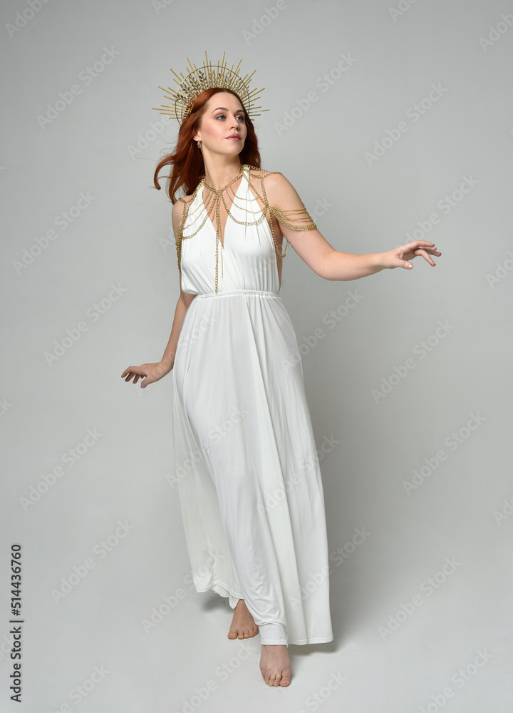 Full length portrait of beautiful red head woman wearing long flowing fantasy toga gown with golden halo crown jewellery, standing pose isolated on a white studio background.
Full length portrait of beautiful red head woman wearing long flowing fantasy toga gown with golden halo crown jewellery, standing pose isolated on a white studio background.