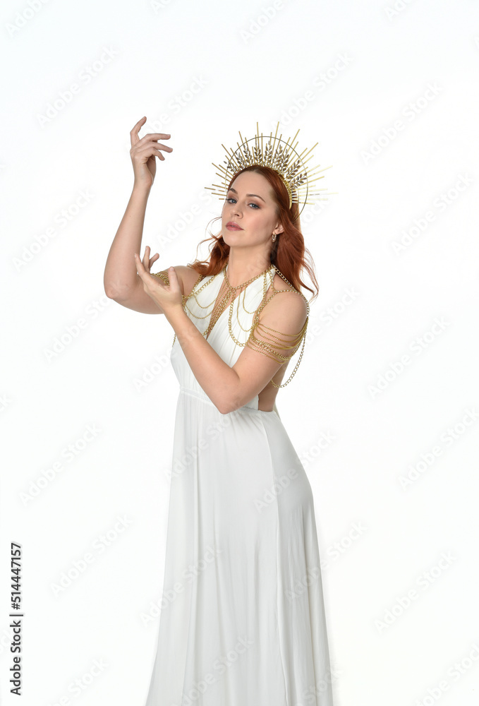 Close up portrait of beautiful red-haired woman wearing long flowing fantasy toga gown with golden halo crown jewellery, creative hand gestures isolated on a white studio background. Close up portrait of beautiful red-haired woman wearing long flowing fantasy toga gown with golden halo crown jewellery, creative hand gestures isolated on a white studio background.