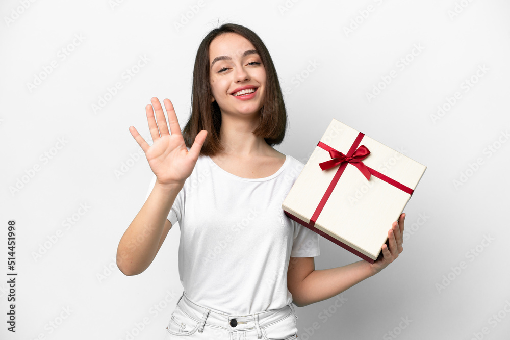 Young Ukrainian woman holding a gift isolated on white background saluting with hand with happy expression Young Ukrainian woman holding a gift isolated on white background saluting with hand with happy expression