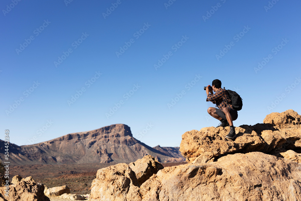 Young man taking pictures on a road trip. Man making memories on the mountain. Young man taking pictures on a road trip. Man making memories on the mountain.