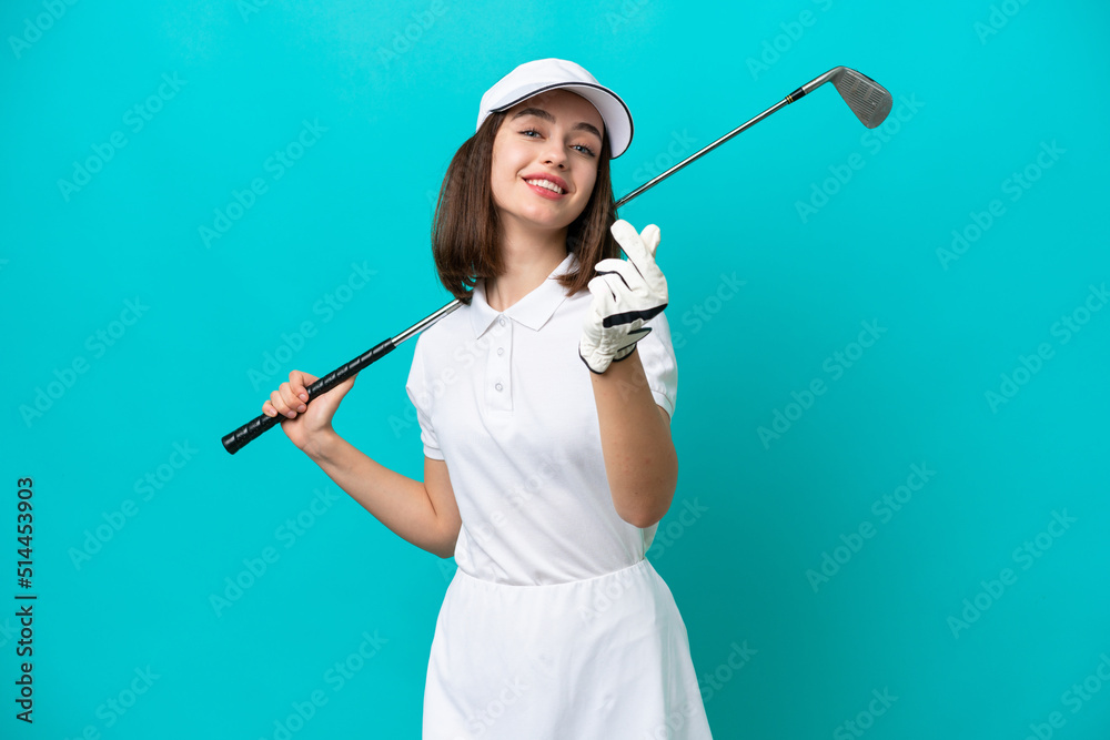 Young Ukrainian golfer player woman isolated on blue background making money gesture Young Ukrainian golfer player woman isolated on blue background making money gesture